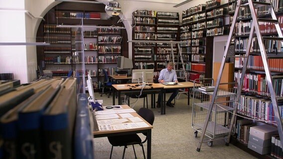 Ein Mann von der Kieler Stadtplanung sitzt an einem Schreibtisch inmitten eines Büros voller Bücher © NDR / SH Magazin 