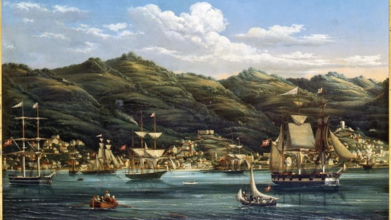 Eine historische Aufnahme zeigt ein Gemälde mit vielen Segelschiffen vor einer Küste mit hügeliger Landschaft. Eine historische Aufnahme zeigt ein Gemälde mit vielen Segelschiffen vor einer Küste mit hügeliger Landschaft.