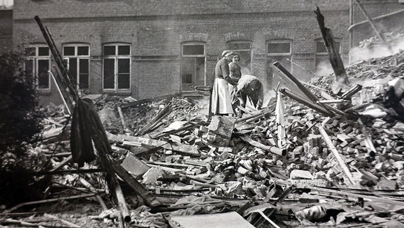Die Betroffenen stehen in den Überresten der zertrümmerten Gebäude. © NDR 