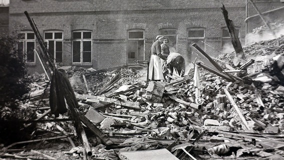 Die Betroffenen stehen in den Überresten der zertrümmerten Gebäude. Die Betroffenen stehen in den Überresten der zertrümmerten Gebäude. © NDR