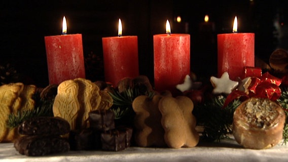 Weihnachtsplätzchen und vier rote Adventskerzen  