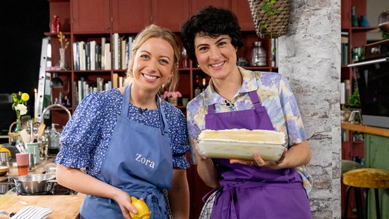 Fernsehköchin Zora Klipp und Konditormeisterin Theresa Knipschild stehen mit einer Form mit Tiramisu in einer Küche. © NDR Foto: Claudia Timmann