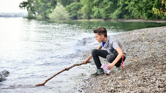 Neles Sohn Niklas (Noah Calvin) fischt Geldscheine aus dem Bodensee. © NDR/SWR/Patrick Pfeiffer 