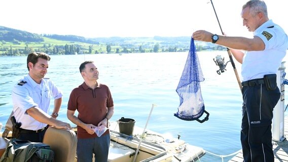 Jakob Frings (Max König, li.) wartet gespannt auf die Erklärung des Schmuckhändlers Florian Arlen (Carsten Strauch, M.) zu dem Fund, den sein Kollege Paul Schott (Tim Wilde, r.) soeben aus dem Wasser gefischt hat. © NDR/ARD/Laurent Trümper 