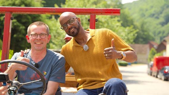 Michael Wagner nimmt Yared vorne auf dem Traktor mit durchs Dorf. © NDR/Antonia Friese 