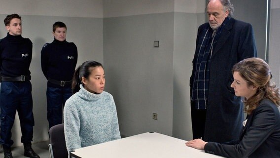 Thomas Borchert (Christian Kohlund, 2.v.r.) und Anwältin Dominique Kuster (Katrin Bauerfeind, r.) kümmern sich um die verängstigte Haushaltshilfe Amihan Singh (Kotti Yun), die in U-Haft sitzt. © NDR/Degeto/Graf Film/Václav S. Sadilek 