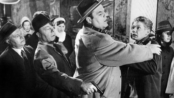 Charly Gibbons (Benno Sterzenbach, Mitte) ist ein gefährlicher Verbrecher, der über Leichen geht. Egon Schilling (Friethjof Vierock, re.) hat allen Grund, sich vor ihm zu fürchten. Zum Glück sind Langfinger-Max (Heinz Rühmann, 2. v. li.) und sein Freund Arthur (Hans Hessling, li.) rechtzeitig zur Stelle, um die Situation zu entschärfen. Charly Gibbons (Benno Sterzenbach, Mitte) ist ein gefährlicher Verbrecher, der über Leichen geht. Egon Schilling (Friethjof Vierock, re.) hat allen Grund, sich vor ihm zu fürchten. Zum Glück sind Langfinger-Max (Heinz Rühmann, 2. v. li.) und sein Freund Arthur (Hans Hessling, li.) rechtzeitig zur Stelle, um die Situation zu entschärfen. © NDR/ARD/Degeto