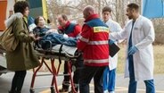 Ella Kling (Ulrike Knospe, 2.v.l.) wird als Notfall ins Johannes-Thal-Klinikum eingeliefert. Sie hat einen Stromschlag erlitten. Vivi (Jane Chirwa, l.) ist in großer Sorge, da ihre Mutter einen Herzschrittmacher trägt. Matteo (Mike Adler, r. mit Komparsen) und Ben (Philipp Danne, 2.v.r.) sind sofort zur Stelle. © NDR/ARD/Jens Ulrich Koch 