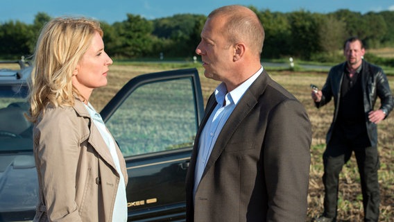 Kommissarin Lindholm (Maria Furtwängler) mit Schlachthofbesitzer Jan-Peter Landmann (Heino Ferch) nach einer Reifenpanne. Im Hintergrund Leibwächter Müller (Marko Dyrlich). © NDR/Christine Schroeder 