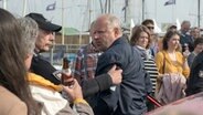 Alex Milberg als Tatort-Kommissar Borowski schaut wütend und wird von einem Mann festgehalten © NDR/Christine Schroeder 