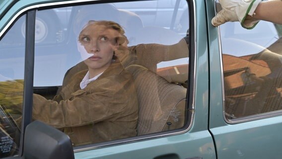 Polizistin Anne Bach (Karoline Schuch) sitzt in einem Auto und blickt einen Mann kritisch an, der vor ihrem Fenster steht. © NDR/Christiane Pausch Fotografie Foto: Christiane Pausch