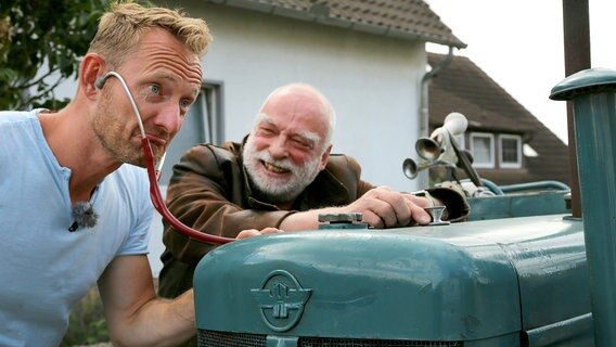 Sven Tietzer (links) und Landarzt Uwe Thies (rechts) mit Stethoskop am Trecker. © NDR 