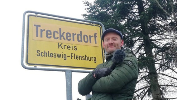 Sven Tietzer vor dem Ortsschild "Treckerdorf". © NDR 