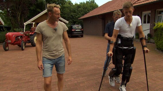 Sven und Linus mit Exoskelett mit Unterstützung von Vater Rudi. © NDR 
