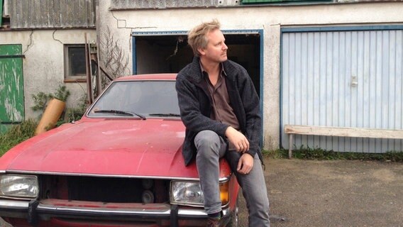 Jens Tanz aus Kiel 25 Jahre später mit seinem ersten Auto: einem Ford Granada. Heute steht er fahruntüchtig in einer Garage bei Rendsburg. © NDR/Lona Media 