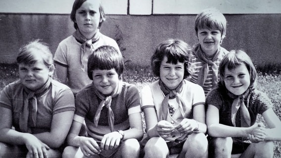 Kinder sitzen in den 1970er-Jahren vor einem Wohnblock in der Güstrower Südstadt. © NDR Foto: Barbara Seemann