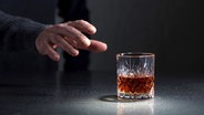 Eine Hand greift zu einem vollen Whiskyglas © colourbox 
