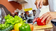 Ein Mann schneidet eine Paprika auf einem Holzbrett. © Colourbox Foto: Pressmaster