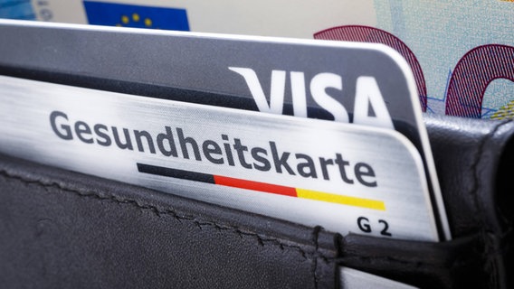 Eine Gesundheitskarte steckt in einem Portemonnaie neben einer Kreditkarte. © imago images/photothek Foto: Thomas Trutschel
