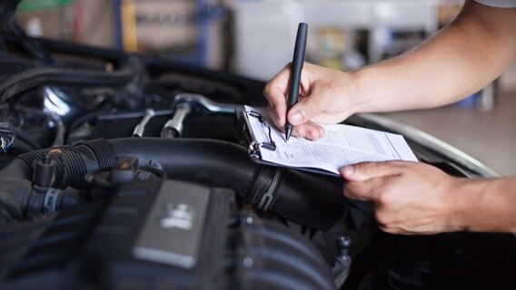 Checkliste wird bei der Überprüfung eines Autos unter der Motorhaube bearbeitet © colourbox Foto: -