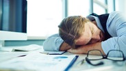 Ein junger Mann schläft auf seinem Bürotisch. © Colourbox Foto: Pressmaster