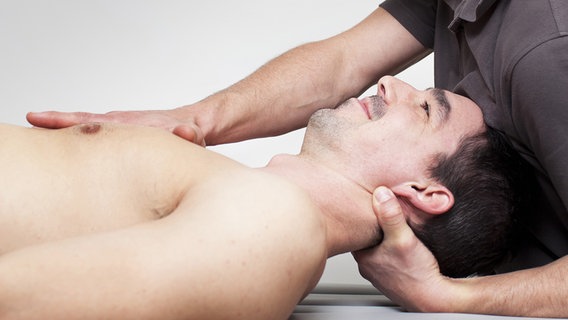 Therapeut hält liegenden Patienten am Nackenbereich fest © Fotolia Foto: Adam Gregor