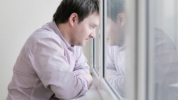 Ein Mann schaut traurig zum Fenster hinaus. © Colourbox Foto: -