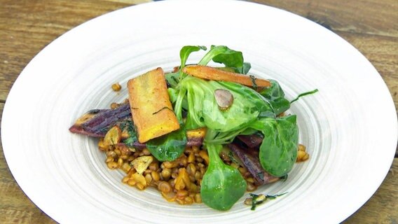 Linsensalat mit Knoblauch-Karotten und Feldsalat auf einem Teller serviert. © NDR 