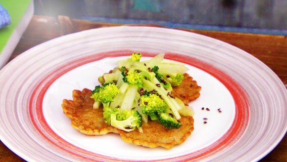 Rosenkohl-Pfannkuchen mit Brokkoli-Fenchel-Gemüse auf einem Teller serviert. © NDR 