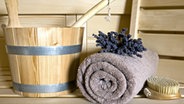 Massagebürste, Handtuch und Aufgusseimer auf einer Saunabank © Panter Media Foto: Michaela Pucher