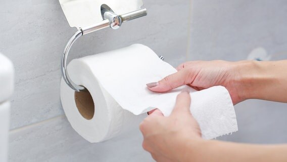 Eine Frau reißt Toilettenpapier von einer Rolle ab. © colourbox 