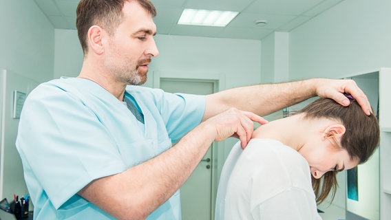 Ein Arzt untersucht die obere Wirbelsäule einer Patientin. © Colourbox Foto: -