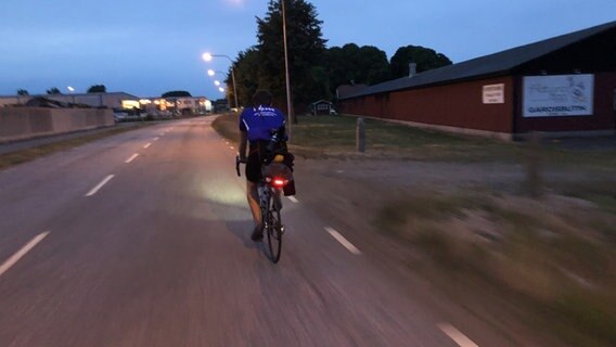 Ronald Schütze fährt in der Abenddämmerung Fahrrad. © NDR 