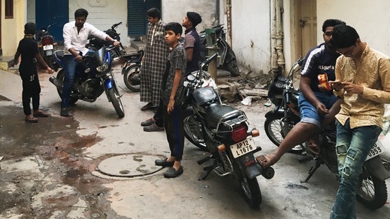 Indische Männer stehen in einem Hinterhof  