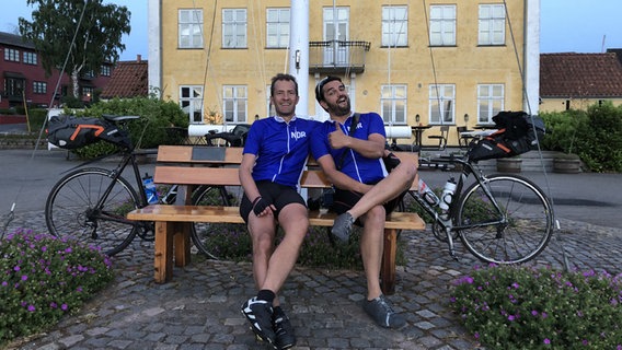 Christian Stichler (li.) und Ronald Schütze sitzen auf einer Bank in Præstø in Dänemark. © NDR 