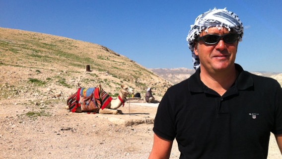 ARD Korrespondent Markus Rosch trägt einen Turban, im Hintergrund liegt ein Kamel © Markus Rosch 