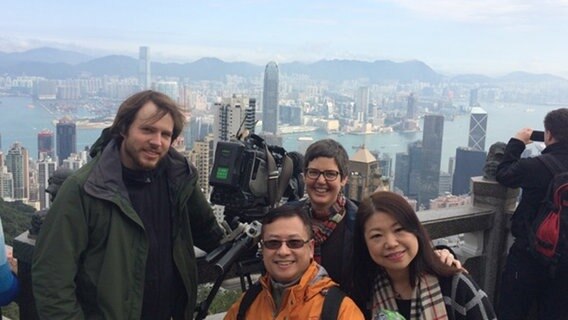 Kameramann Kristian Baum, Tonmann Eric, Korrespondentin Sascha Storfner und Producerin Vivian (v.l.n.r.) vor der Skyline von Hongkong am Victoria Peak.  