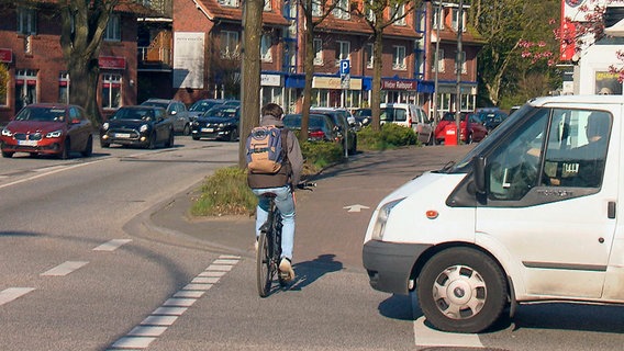 Ein Fahrradfahrer fährt knapp vor einem Transporter über Straße. © NDR 
