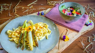 Baked asparagus with fettuccine and hollandaise sauce and a wild herb salad, served on rustic blue-gray plates.  © NDR/doclights Photo: Marc Vorwerk
