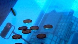 Euromünzen liegen auf dem Spiegelbild eines Bankturms. © NDR 