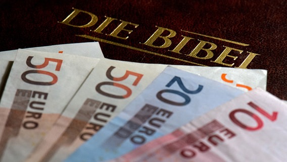 Mehrere Euro-Scheine liegen auf einer Bibel. © picture alliance / ZB Foto: Arno Burgi