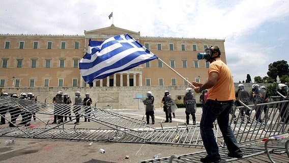 Ein Demonstrant mit Gasmaske schwenkt die griechische Fahne © imago stock&people 