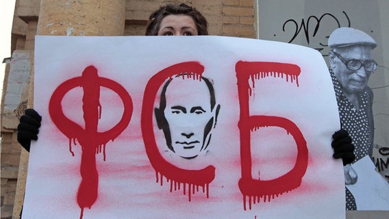 Eine Demonstrantin hält ein Plakat mit dem Gesicht von Putin und der Aufschrift "FSB" hoch. © picture alliance / dpa Foto: Maxim Shipenkov