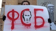 Eine Demonstrantin hält ein Plakat mit dem Gesicht von Putin und der Aufschrift "FSB" hoch. © picture alliance / dpa Foto: Maxim Shipenkov