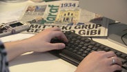 Auf einem Schreibtisch liegen türkische Zeitungen, eine Frau arbeitet am Computer © NDR 