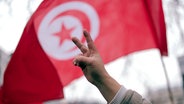 Victory-Zeichen vor tunesischer Fahne © picture alliance / dpa Foto: Jörg Carstensen