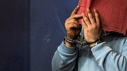 Ein verurteilter Mörder versteckt sein Gesicht hinter einem Aktenordner © picture alliance, NDR 