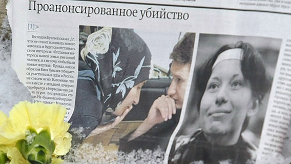 Eine Zeitungsausschnitt mit Blumen und Kerzen zum Gedenken an die ermordeten russische Journalistin Anastasia Baburowa und den Menschenrechtler Stanislaw Markelow. © epa/Sergei Chirikov Foto: Sergei Chirikov
