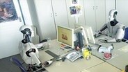 Roboter sitzen an Schreibtischen mit PCs © NDR 