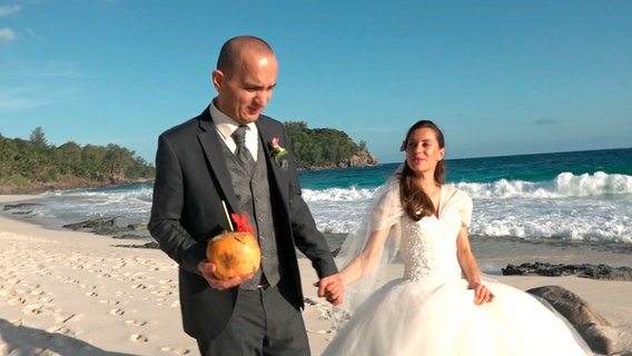 Urlaub auf den Seychellen – oder gar dort heiraten? Die Inselgruppe ist für viele ein Traum, vor allem für Deutsche, die hier die Gästeliste zahlenmäßig anführen. - Hochzeitspaar am weißen Strand © NDR/WDR 